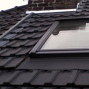 Rénovation d'un toit de maison en tuiles noires avec velux